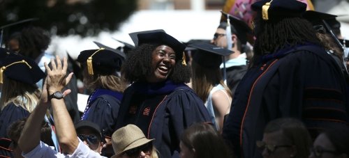 Young woman in a cap and gown looks over her shoulder laughing