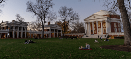 The UVA Rotunda shot from the Lawn at dusk with students studying as they sit on the grass