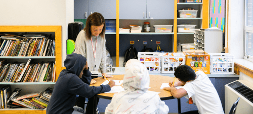 A teacher working with students at a classroom table