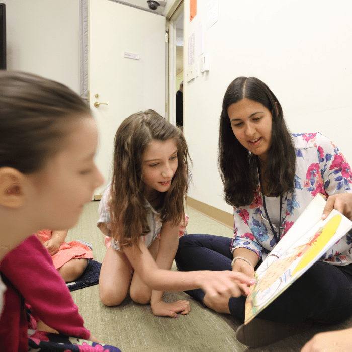 A speech language therapist reading a book to a group of children.