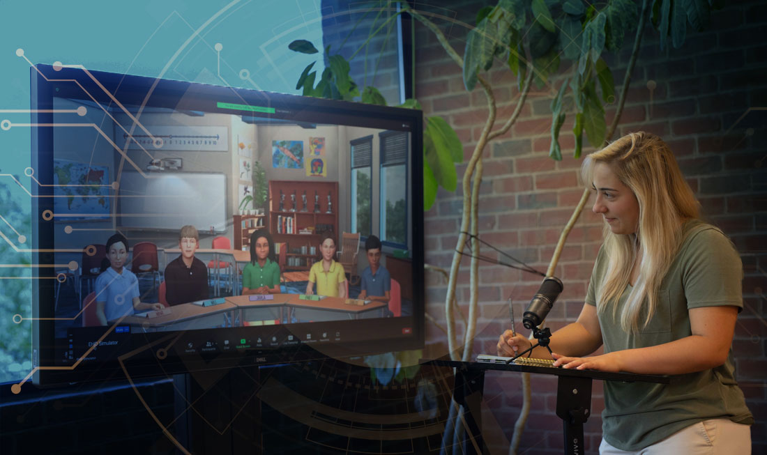Woman stands, writing at a table in front of a screen showing a virtual classroom of students.