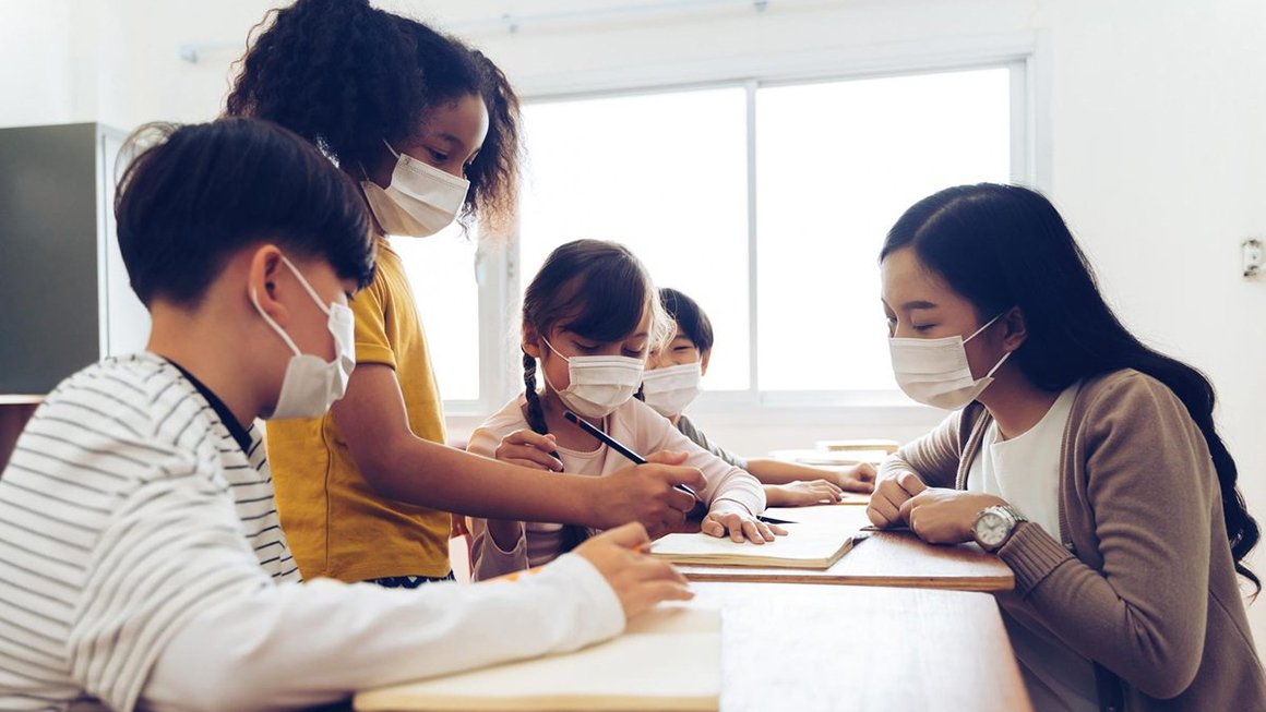 Teacher crouches at table with four students