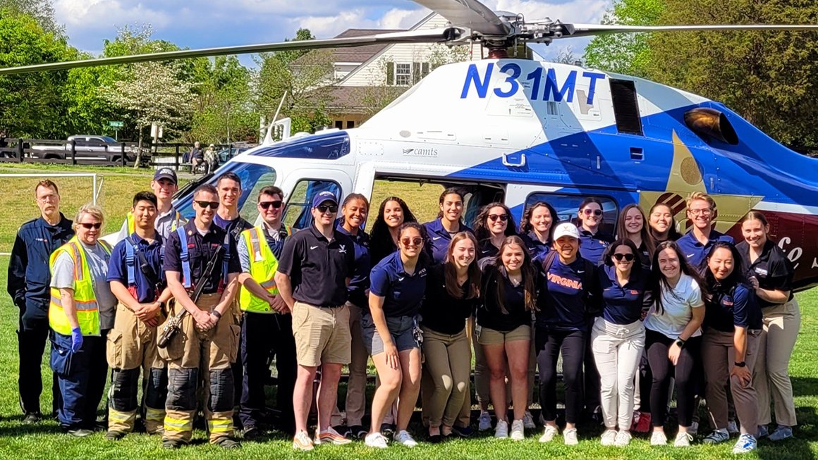 UVA students and emergency personnel stand in front of a helicopter used for emergency transport
