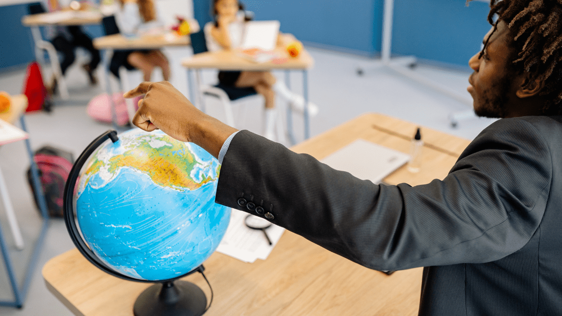 A teacher points at a globe
