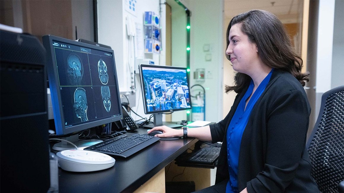 Researcher Kazlin Mason sits at a computer reviewing brain scan images