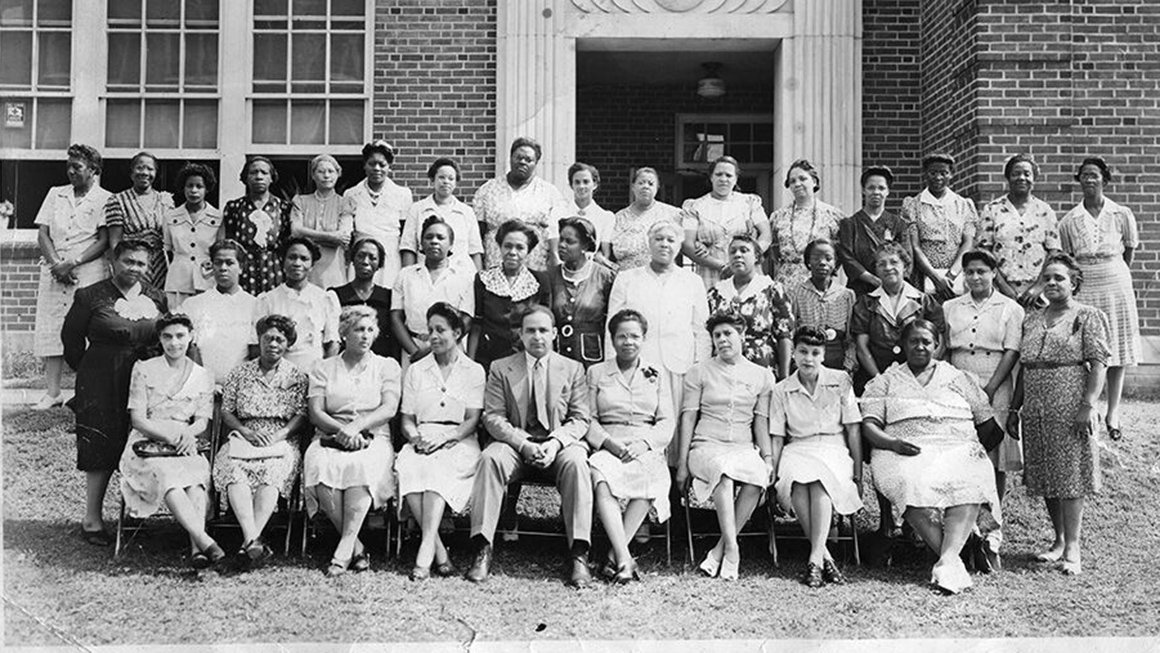 A black and white image of 3 rows of African-American teachers. The back two rows are standing and the front is seated.