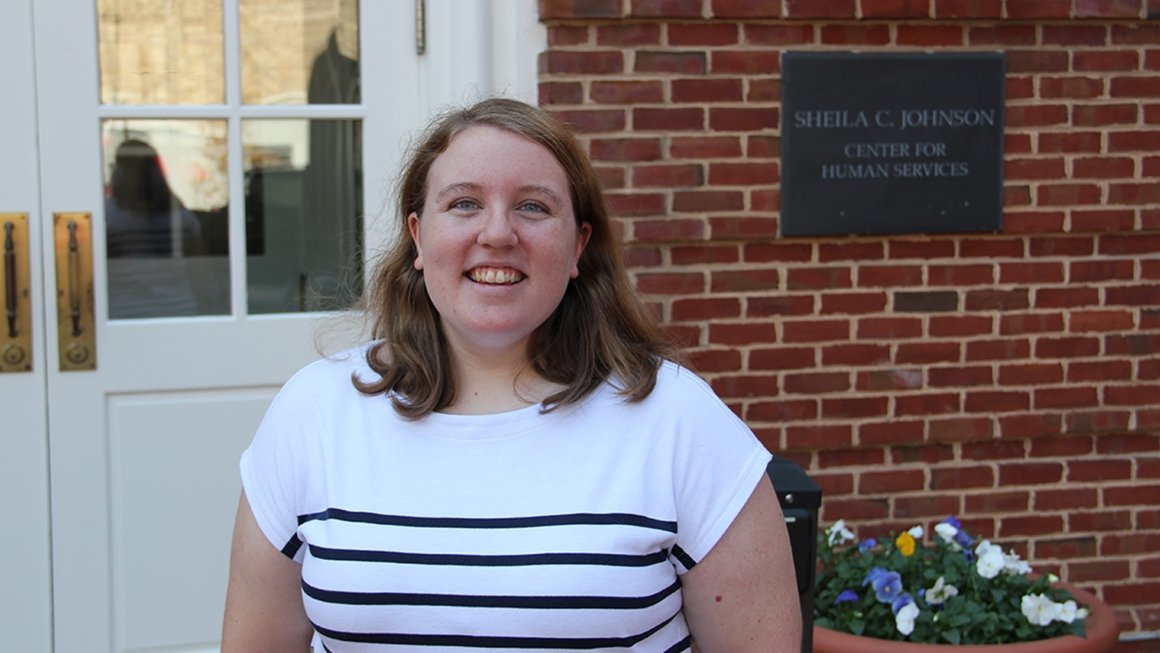 Kellyanne Tyner standing in front of a brick building with a plaque that says "Sheila C. Johnson Center for Human Services"