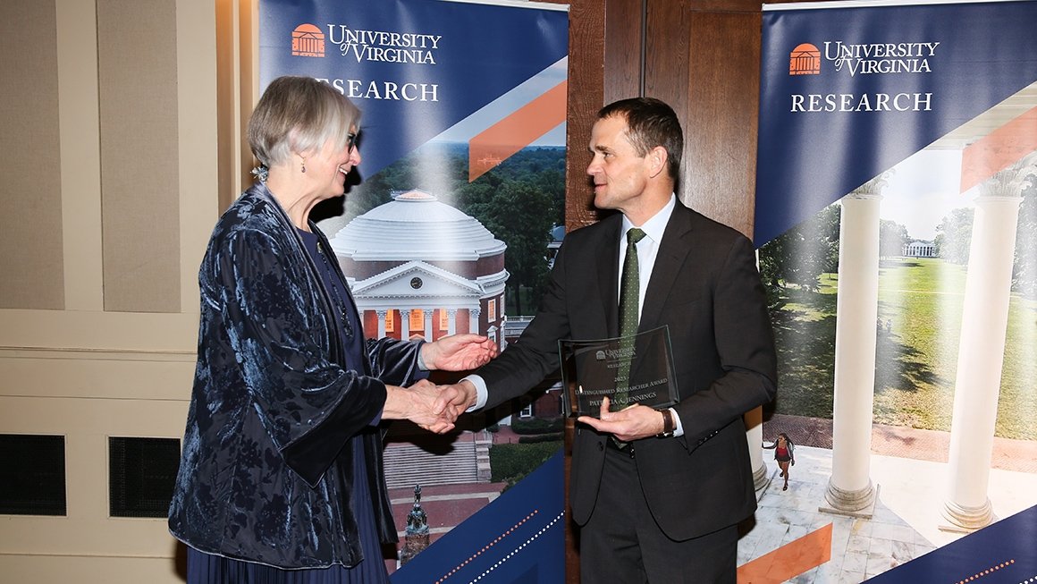 Professor Tish Jennings shakes hands with UVA President Jim Ryan as she accepts her award.