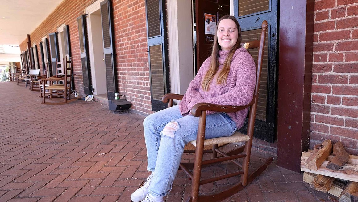 Rachel Moore sits in a rocking chair outside the door of her room on the Lawn.