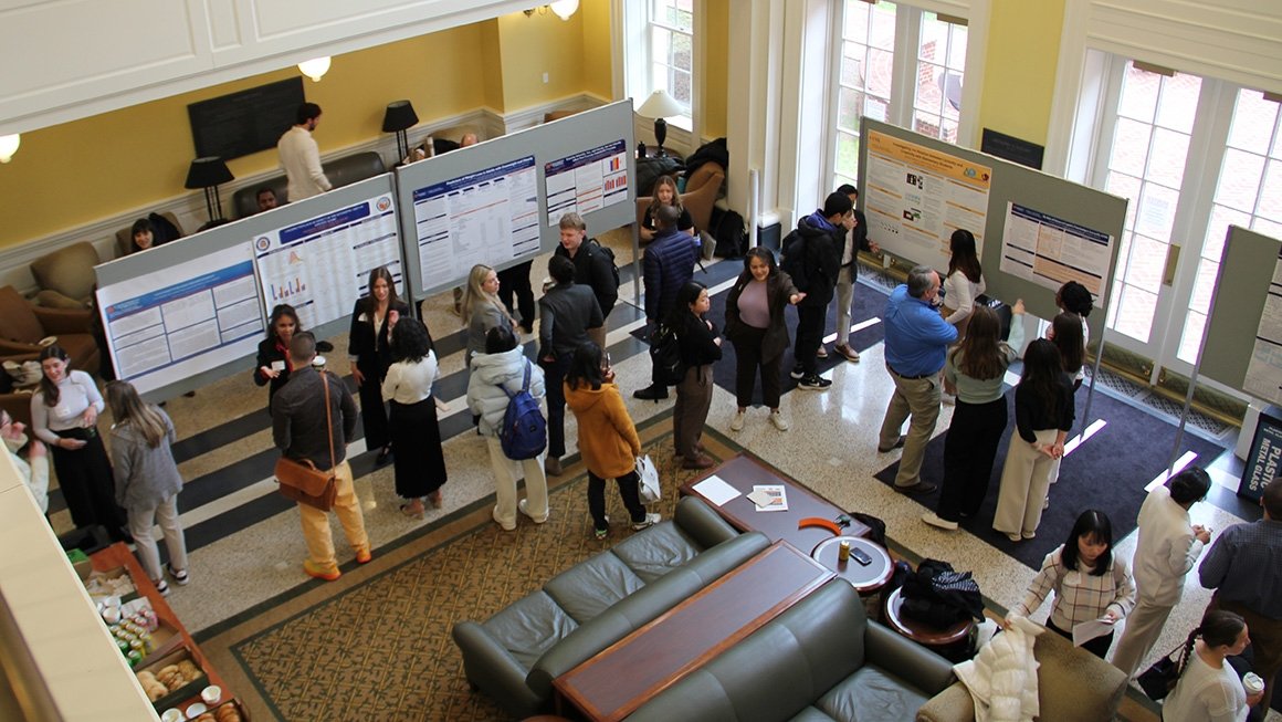 Students gather around a display of research posters