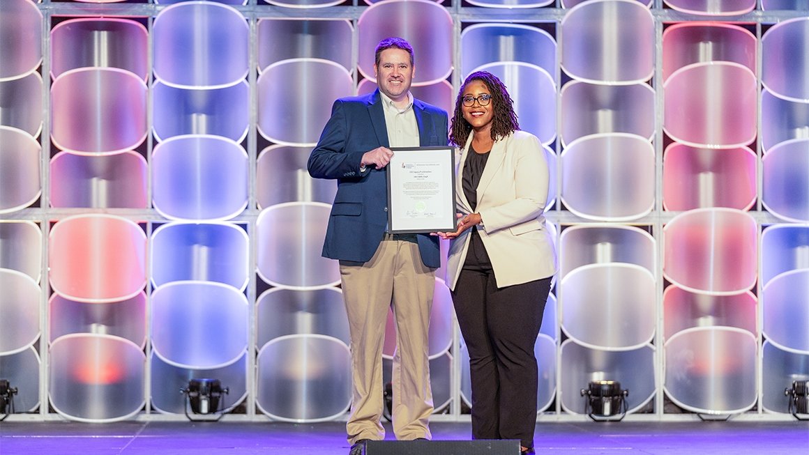 Professor Michael Kennedy stands on a stage accepting an award