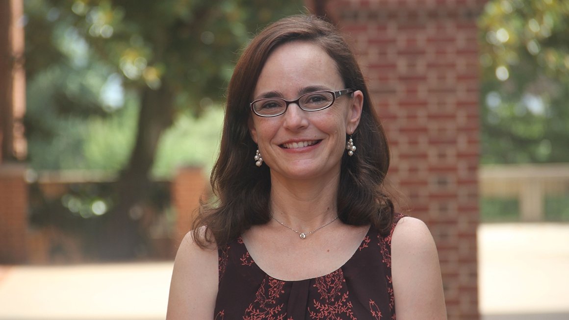 Judy Paulick stands outside and smiles at the camera.