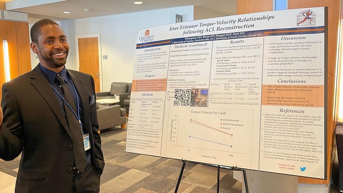 Xavier Thompson smiles and stands in front of a research poster featuring his research