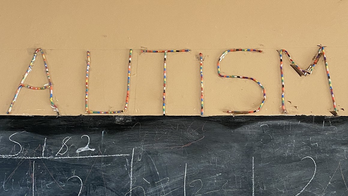 AUTISM written in beads above a chalkboard