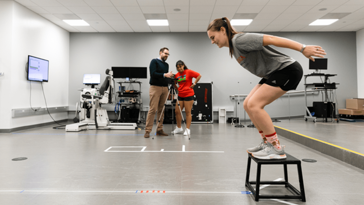 Student about to jump off a box in the exercise and sport injury lab.