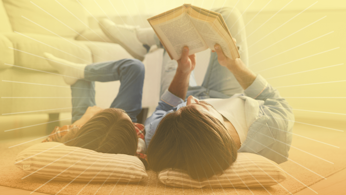 Adult and child lay on pillows both reading a book.