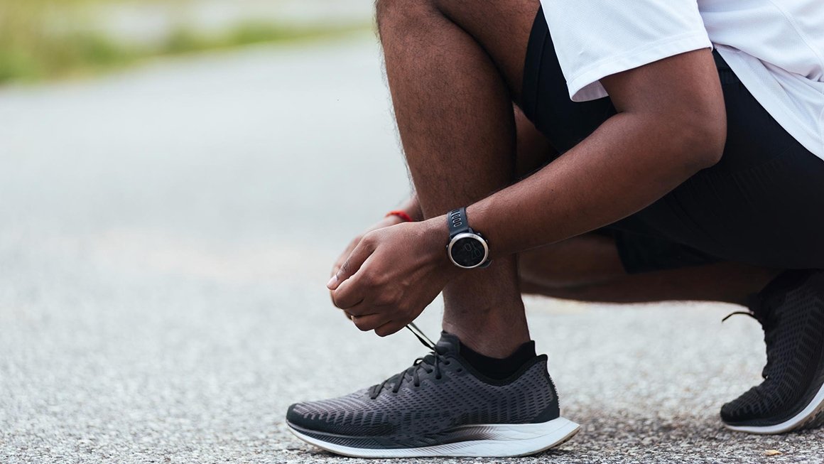 Person kneels to tie their sneaker