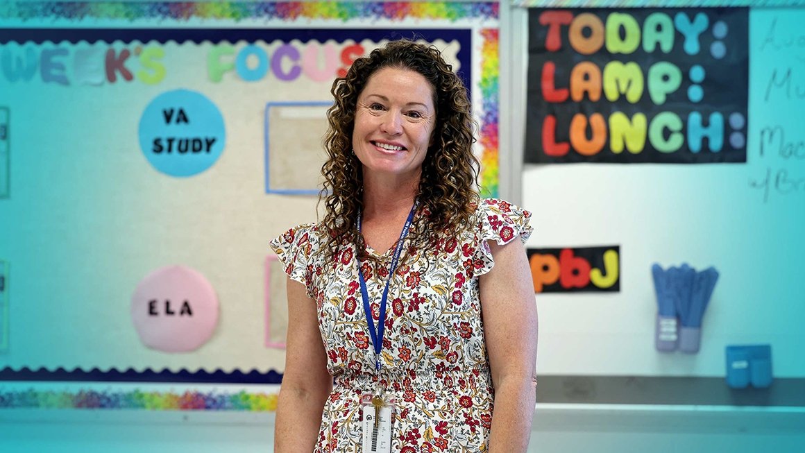Anne Duckworth stands in front of a colorful bulletin board in her classroom.