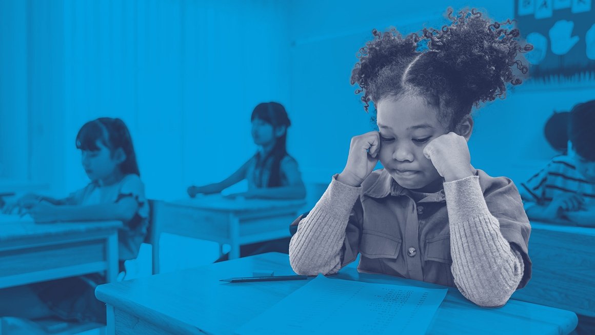 Young student sits at her desk concentrating on a piece of paper.