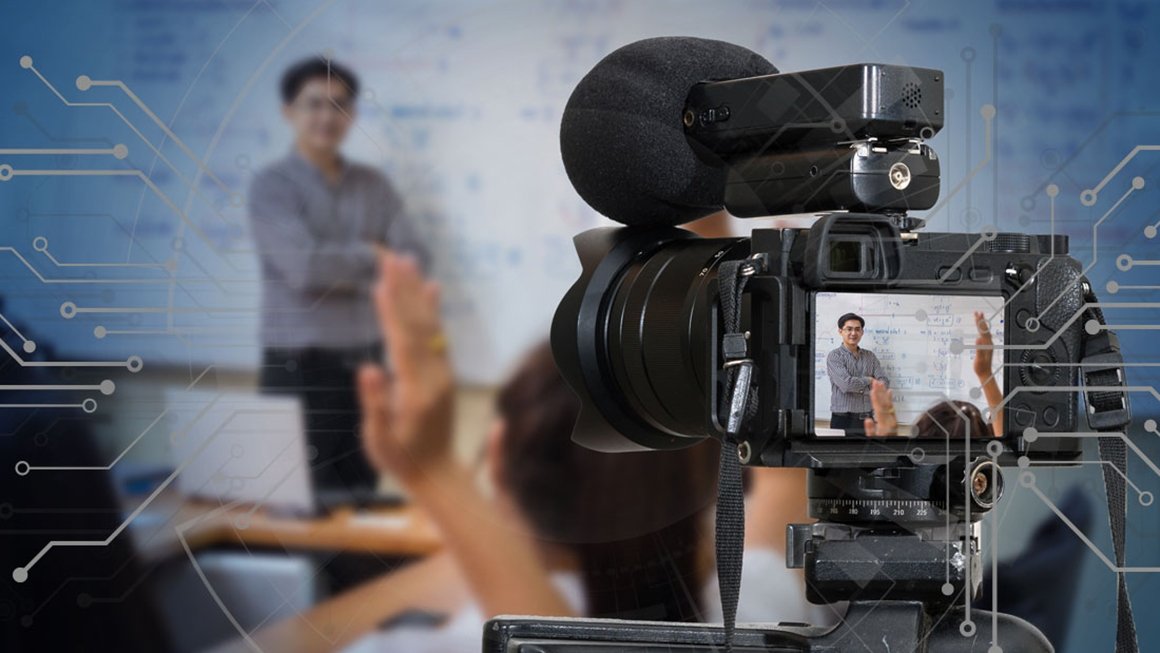 Video camera placed in front of a teacher standing in front of a whiteboard.