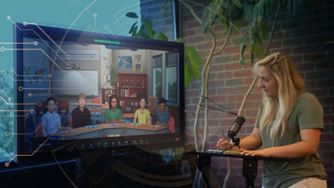 Woman stands, writing at a table in front of a screen showing a virtual classroom of students.
