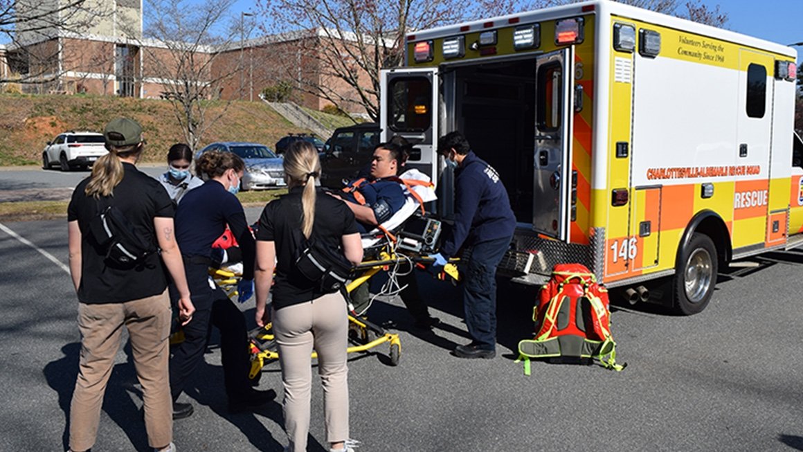 People gathered around a person on a stretcher being loaded into an ambulance