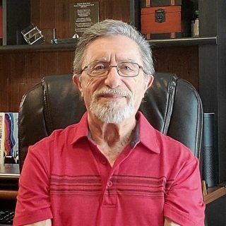 Daniel Berch profile picture. Daniel is seated wearing a red collared shirt and glasses. He is looking at the camera.
