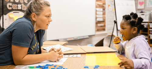 A teacher and a child working together at a classroom table