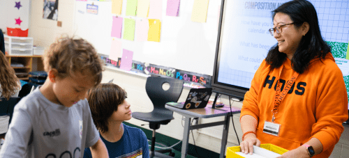 A teacher speaking to two students in a clasroom