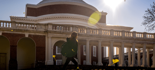 A student walking across the UVA Lawn with the Rotunda in the background