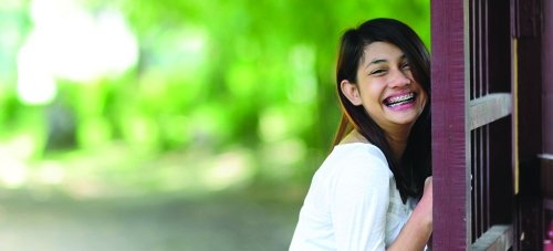 Young woman opening door and smiling