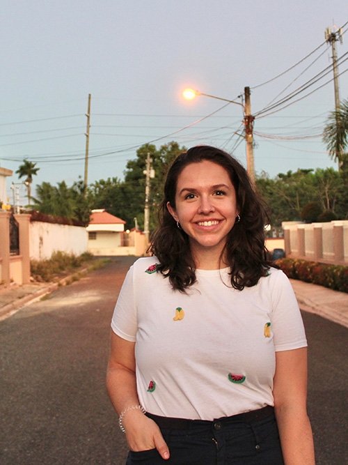 Katie MacDonald, wearing a white T-shirt, stands on a street in the Dominican Republic