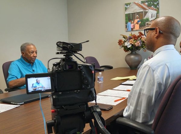 sam-foster-sr_tim_checkerboard.jpg Professor Alridge sits at table next to camera that is pointed at Mr. Sam Foster, Sr. across the table