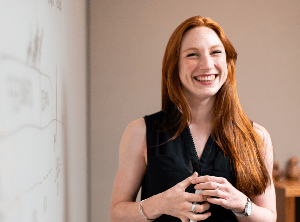 An educator smiling in front of a whiteboard