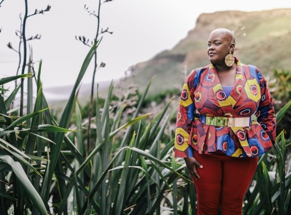 Checkboard_Common-Read_Author-Sonya-Renee-Taylor_June-2023.jpeg Author Sonya Renee Taylor in a field looking off to left