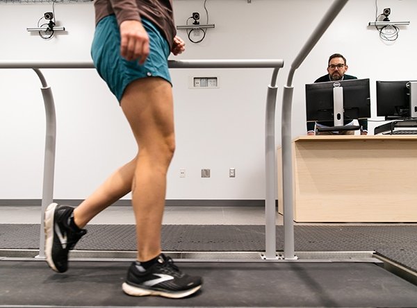 easil-lab_checkerboard_walking-assessment_2023-09-21.jpg Man sits behind a computer screen in background. Woman walks on treadmill in foreground.