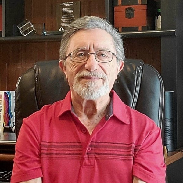Daniel Berch profile picture. Daniel is seated wearing a red collared shirt and glasses. He is looking at the camera.