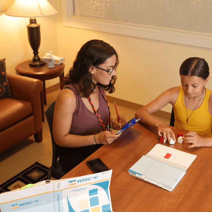 a clinician working with a patient on an activity at a table.