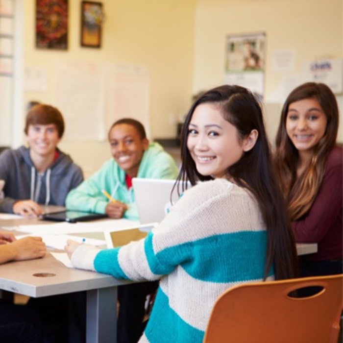 Students sit around table in boardroom