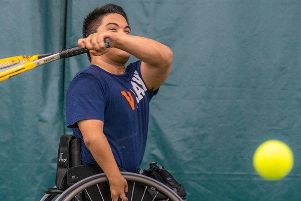 A man in a wheelchair playing tennis