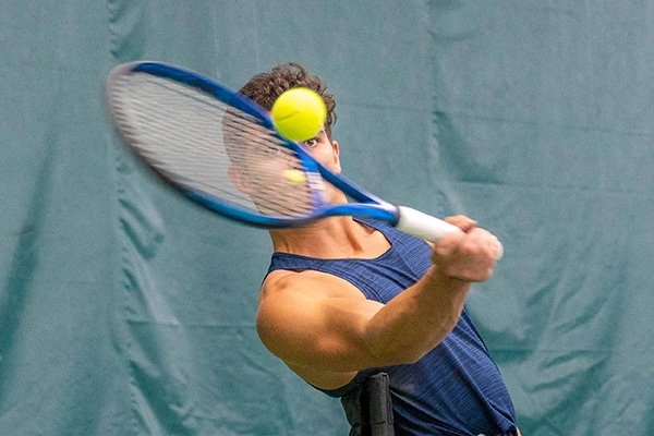 Action shot of a man hitting a tennis ball with a racket