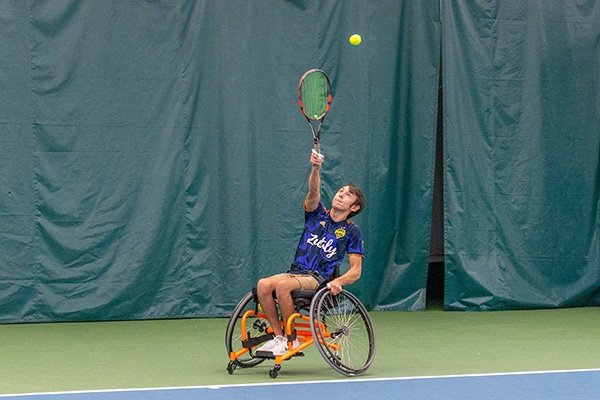 A man in a wheelchair playing tennis