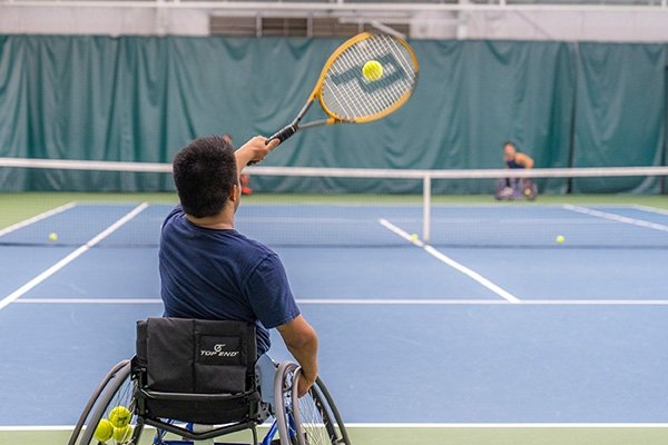 Man in a wheelchair playing tennis