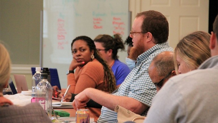 Students participate in a discussion around a table