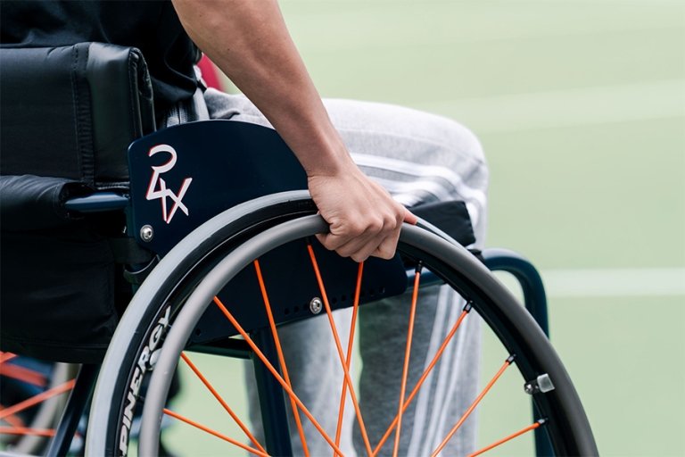 Close-up of a student's hand gripping the wheel of their wheelchair