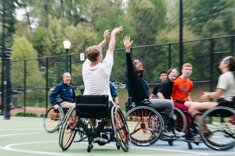 Students play wheelchair basketball on an outdoor court