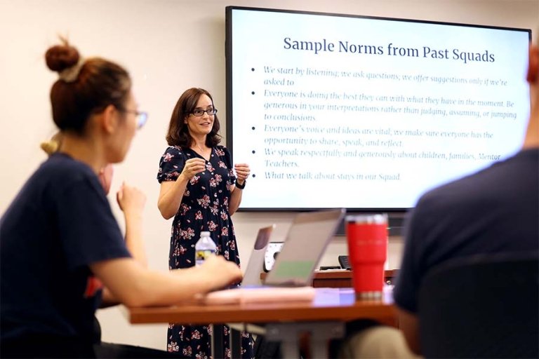 Judy Paulick stands at the front of a classroom teaching college students