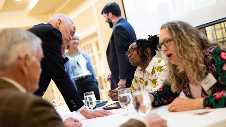 Panelists chat with attendees at a table following an event