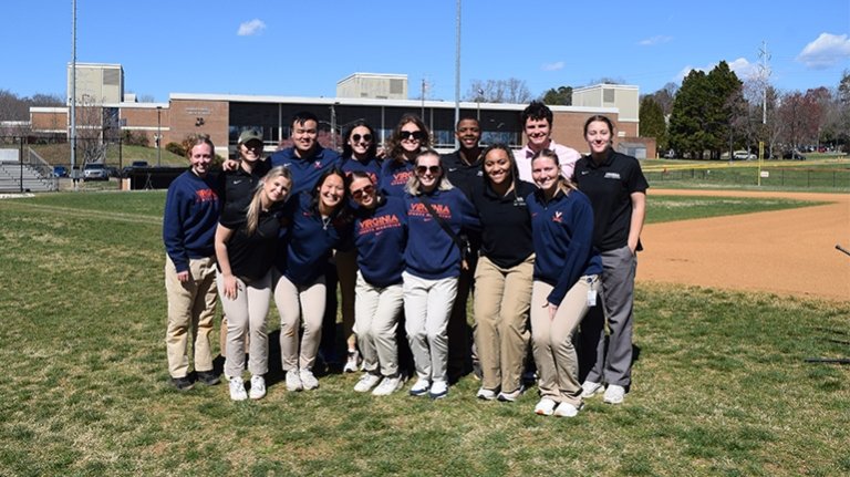 A group of students standing on a baseball field smiling at the camera