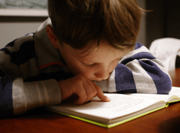 A child reading a book at a table